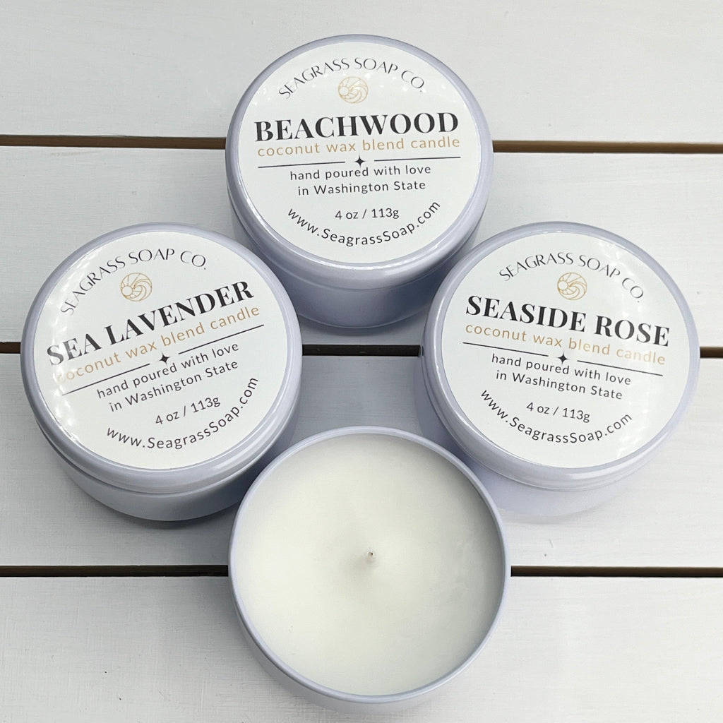 Our Coastal Candle Collection includes beachwood, lavender and seaside rose scents in 4oz white travel tins.