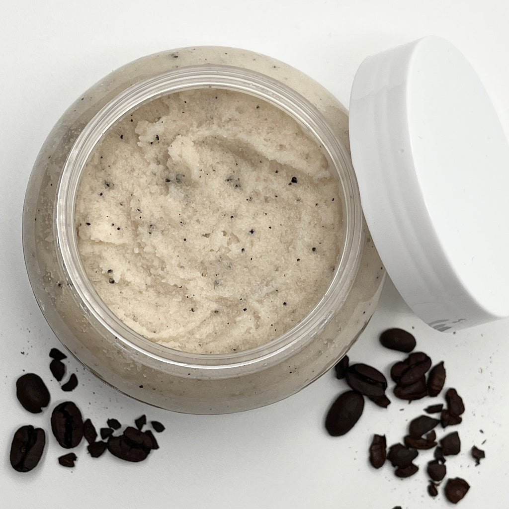 Open jar of coffee scrub with coffee beans on a white background