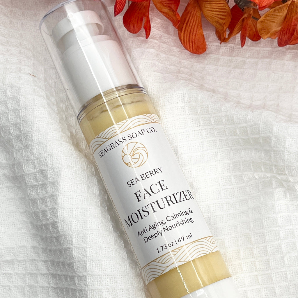 Tube of Sea Berry Face Moisturizer from Seacran Soap Co. on a textured white background with orange flowers.