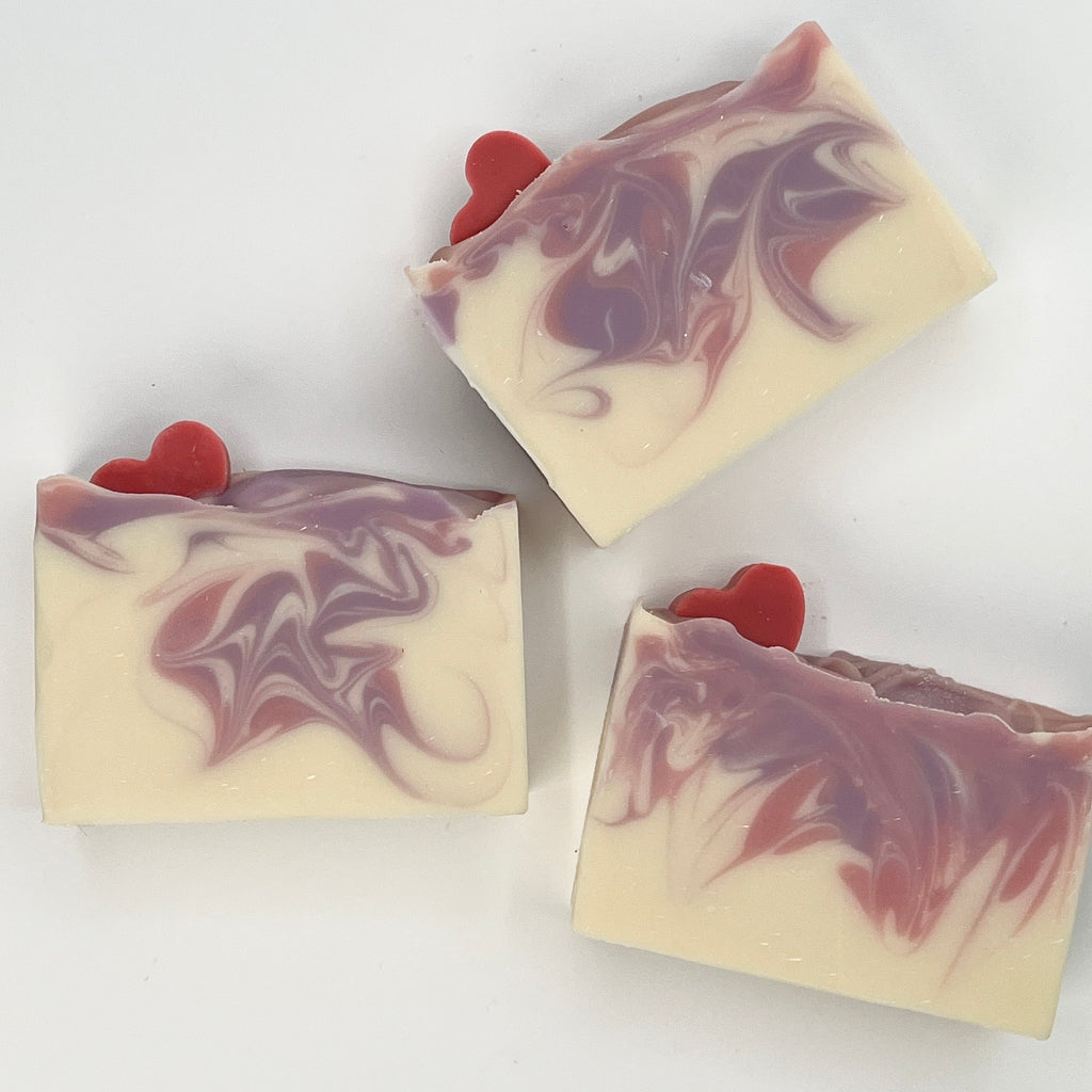 Three swirled soap bars with pink hearts on a white background
