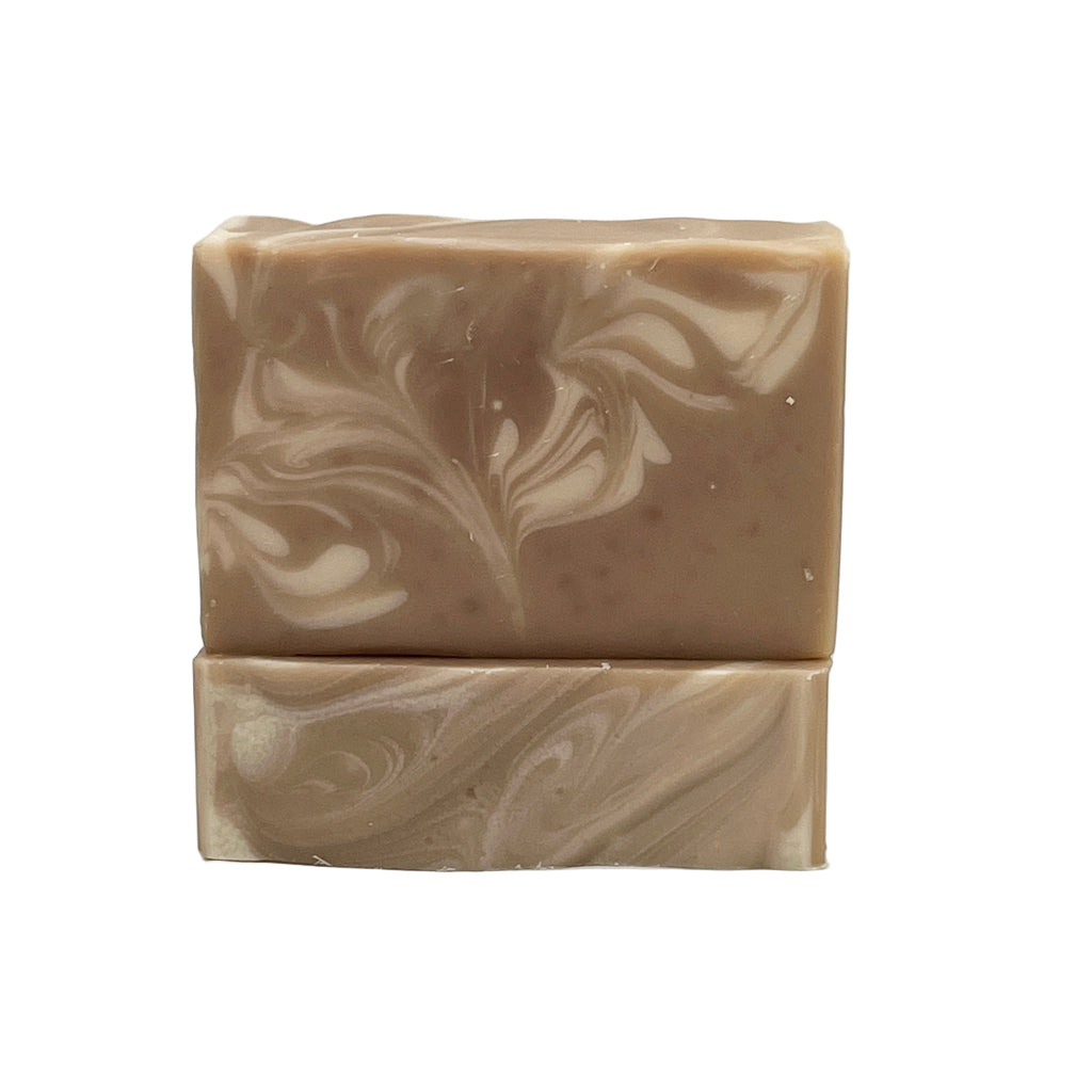 Two bars of oats, milk and honey soap with cream swirled pattern on a white background