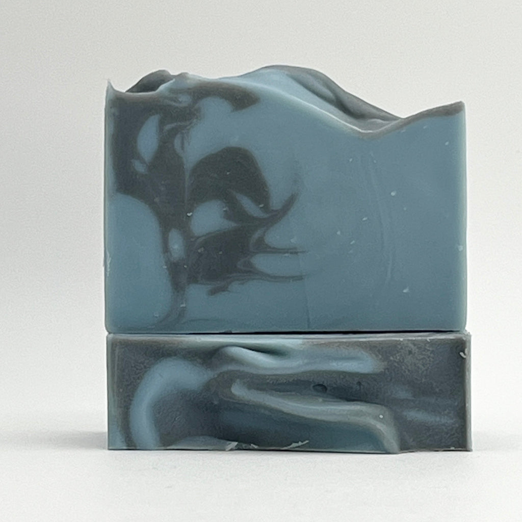 Salty Mariner ocean water soap bar with a blue base and a black swirl on a white background by Seagrass Soap Co.