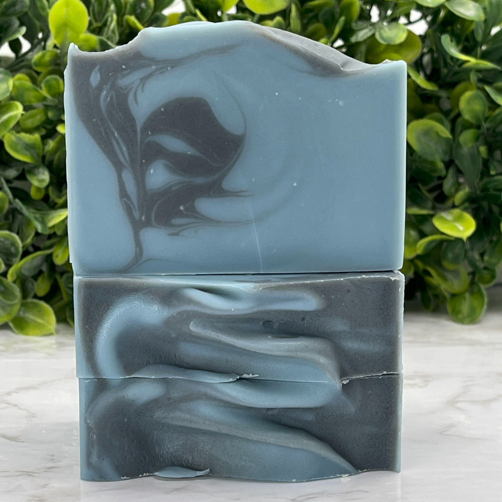 Salty Mariner soap bar, handmade on Camano Island, Washington on a white marble surface with greenery in the background.