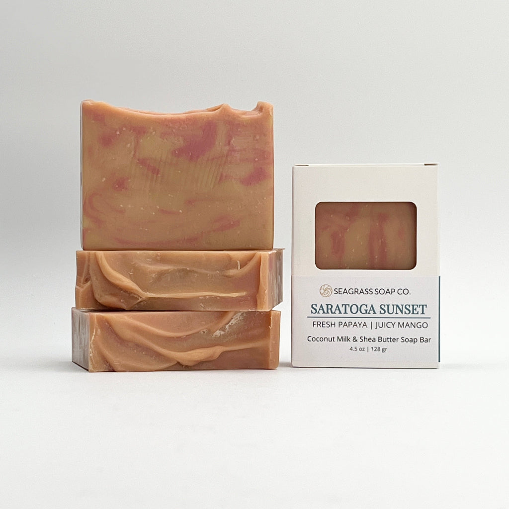 Three Papaya and Mango scented Saratoga Sunset ocean water soap bars and packaging on a white background.