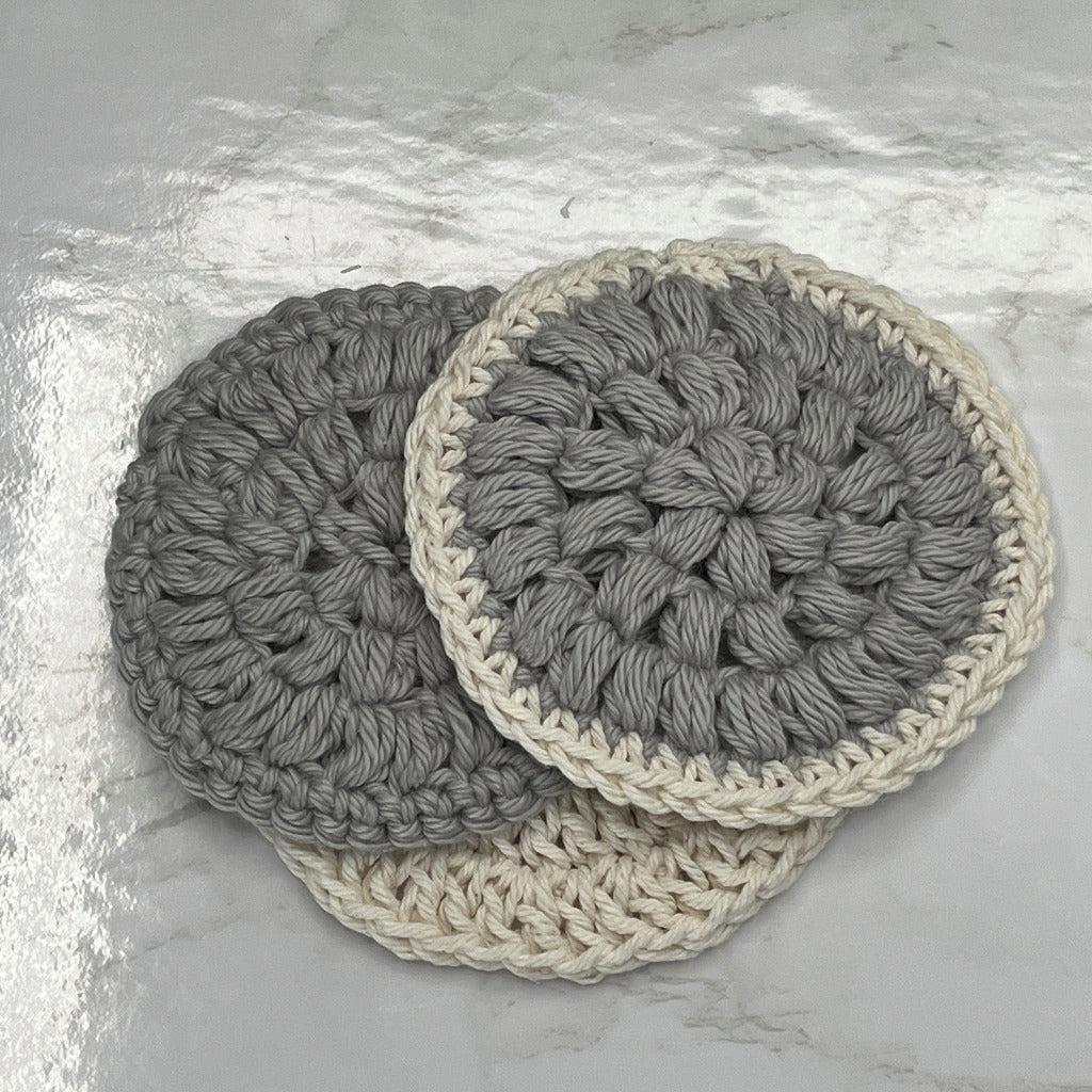 Set of 3 facial scrubbie rounds for face cleaning in a solid gray, gray with a cream edge and solid cream color.