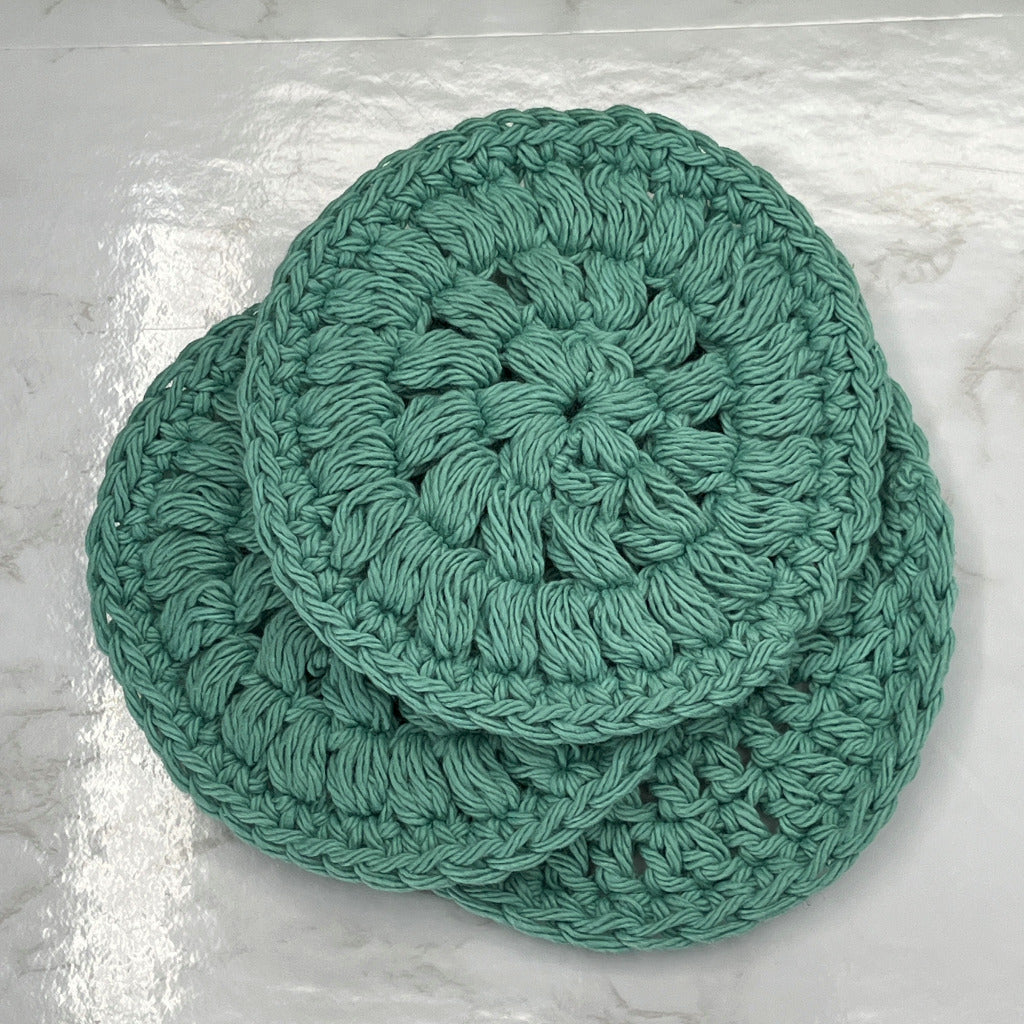 Set of three face cleansing round scrubbies in solid green color.