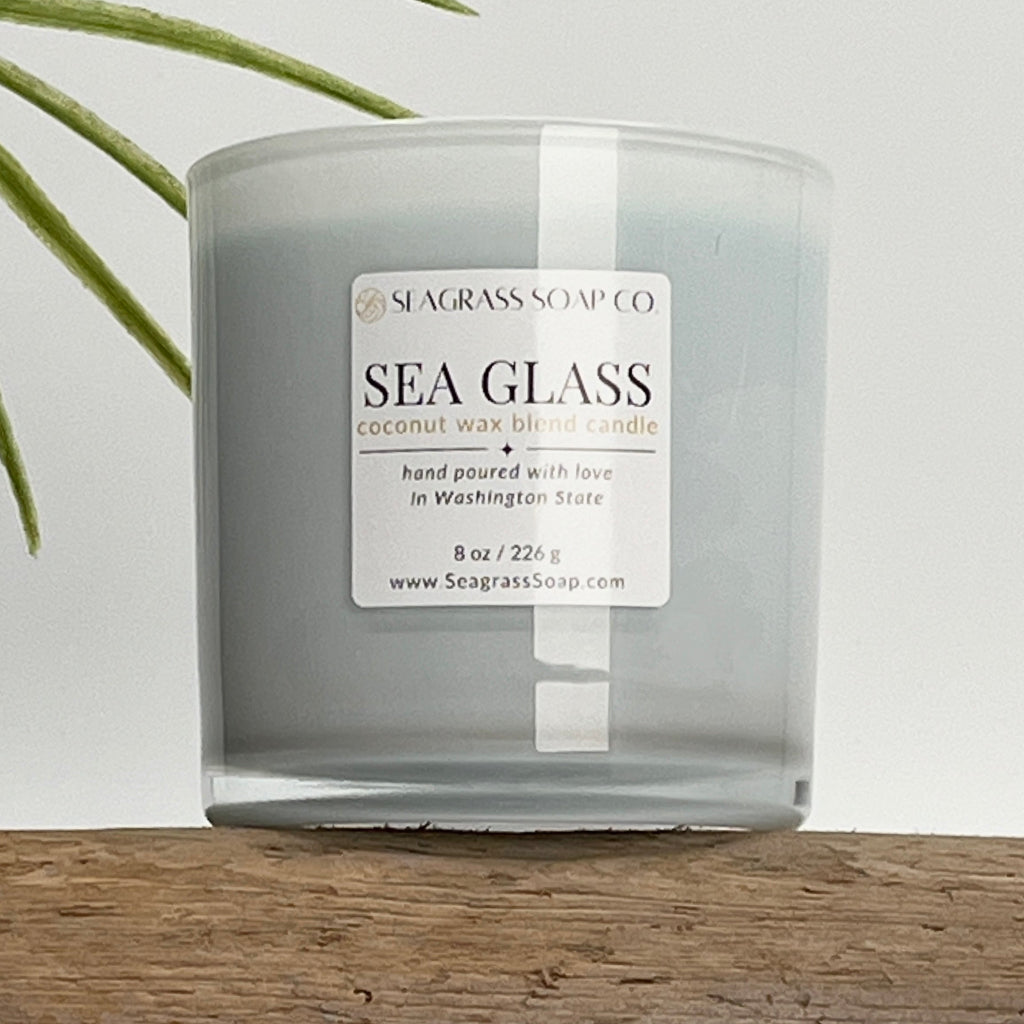 Sea Glass candle from Seagrass Soap Co on a piece of driftwood with a white background