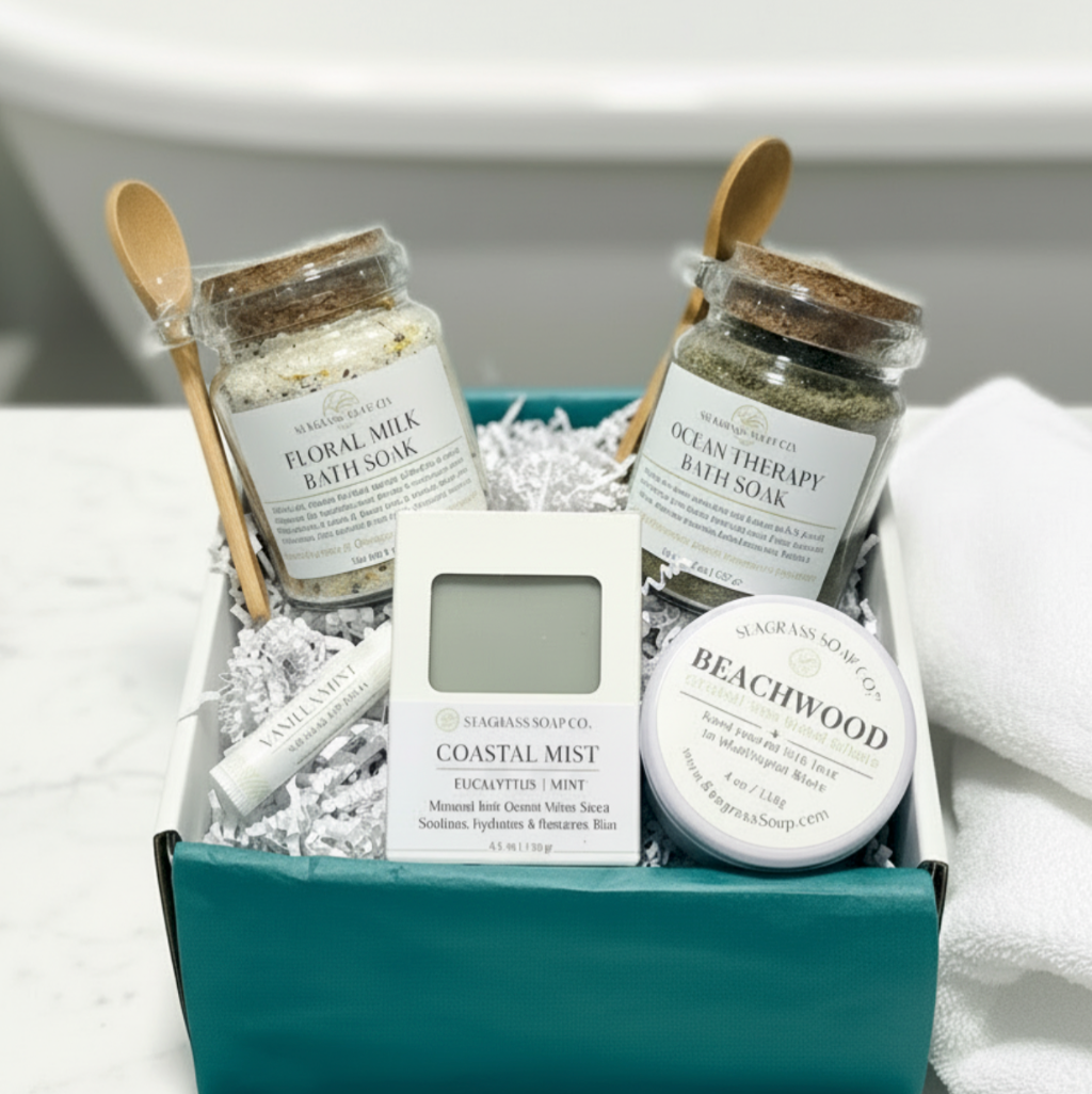 Two bath soak jars jars, 2 wooden spoons, a bar of soap, a lip balm and a small candle in a white box with teal tissue.