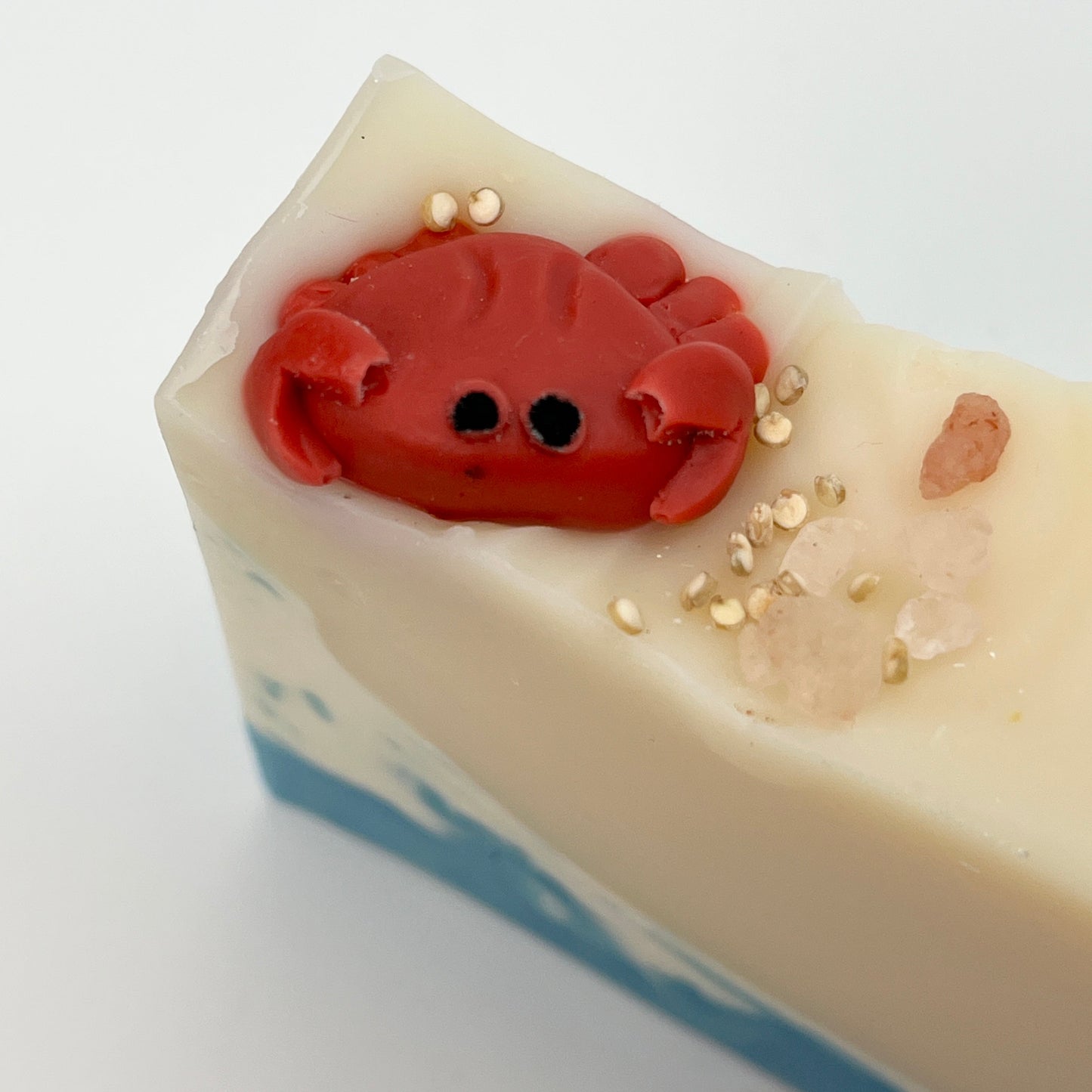 A close up view showing a handmade crab soap sitting on top of or bar soap on a white surface.