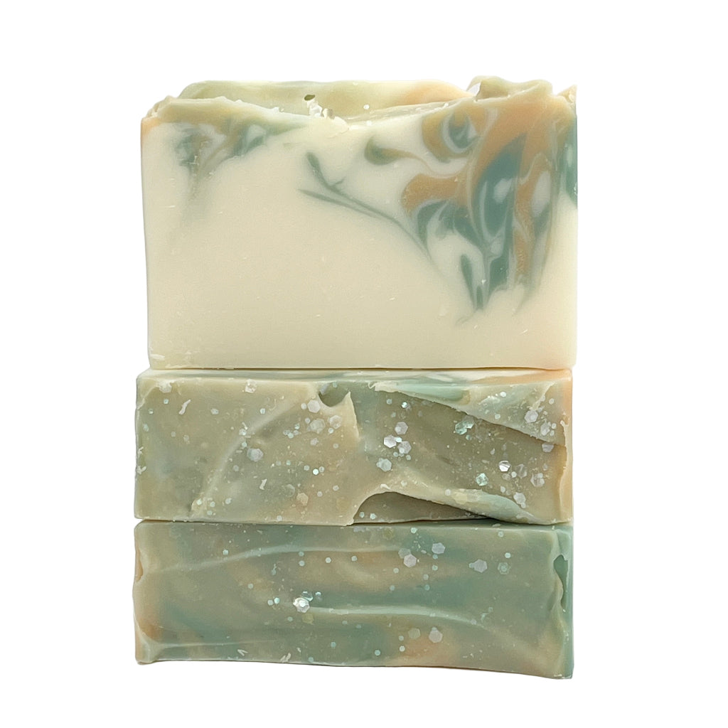 Three bars of white tea and ginger soap bars with swirled pattern on a white background