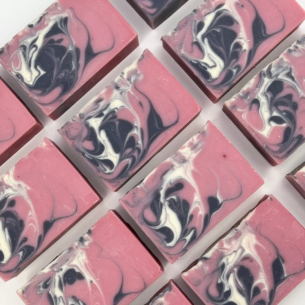 Multiple Wild Berries soap bars and swirl design on a white surface