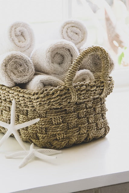 Two starfish sitting by a natural basket filled with rolled towels