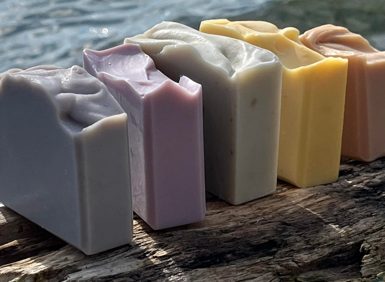 Five bars of soap on a piece of driftwood at the beach