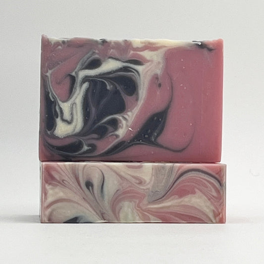 Two marbled soap bars with pink, black, and white swirls on a light gray background.