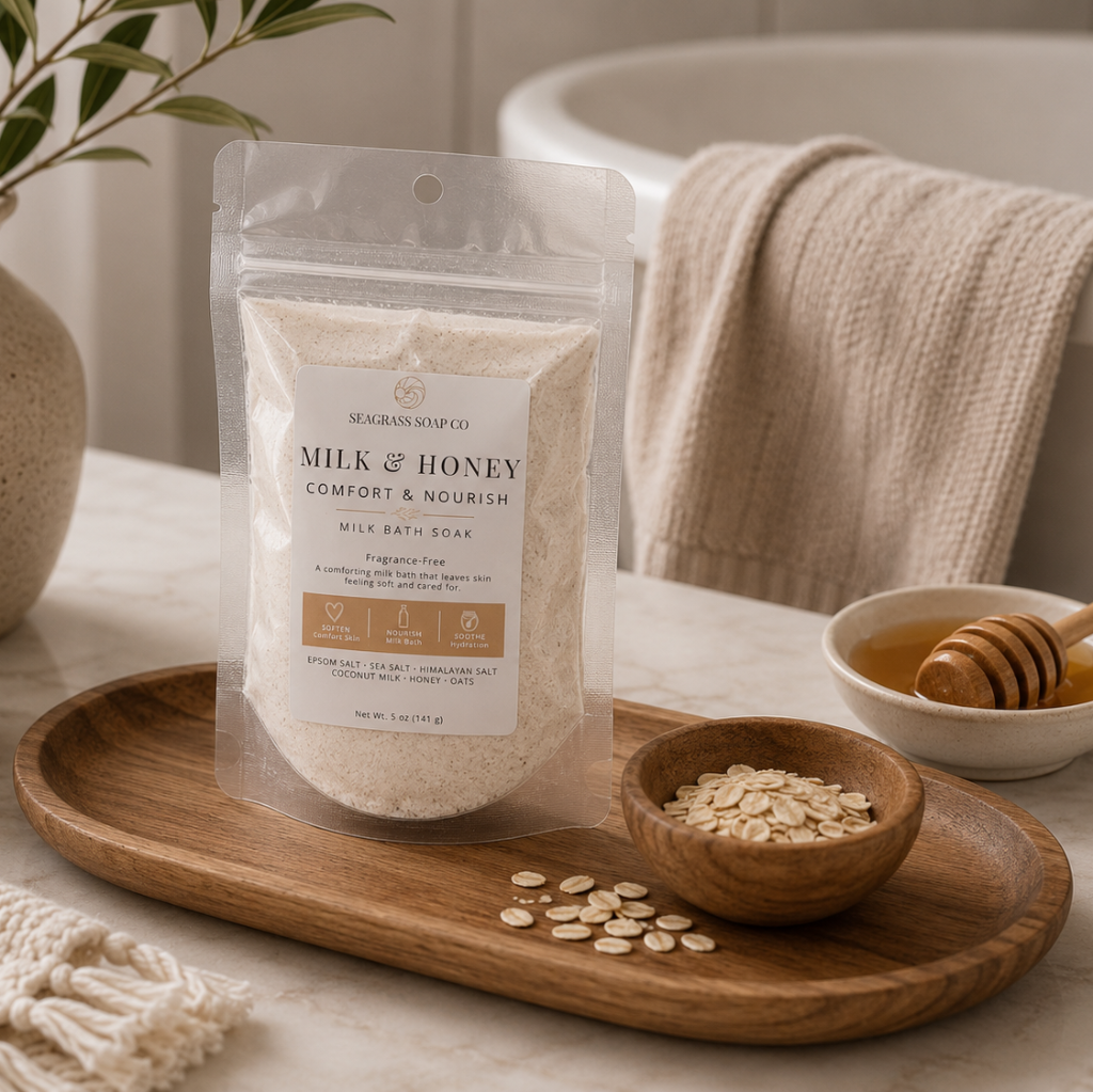 Milk and honey milk bath soak package displayed on a wooden tray with a bowl of oatmeal and honey in a bathroom setting