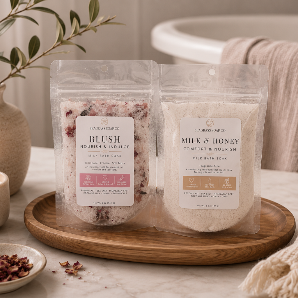 Two milk bath soak packages displayed on a wooden tray in a bathroom setting