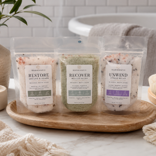 Three mineral bath soak packages displayed on a wooden tray in a bathroom setting