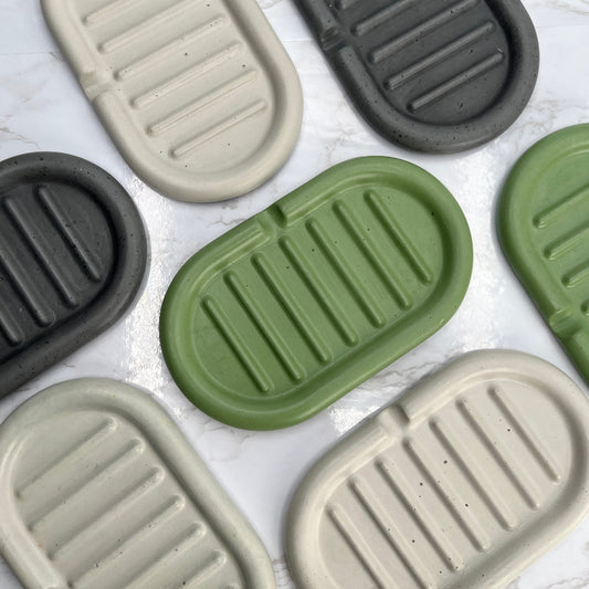 Concrete self-draining soap dishes in three colors, grey, green and cream