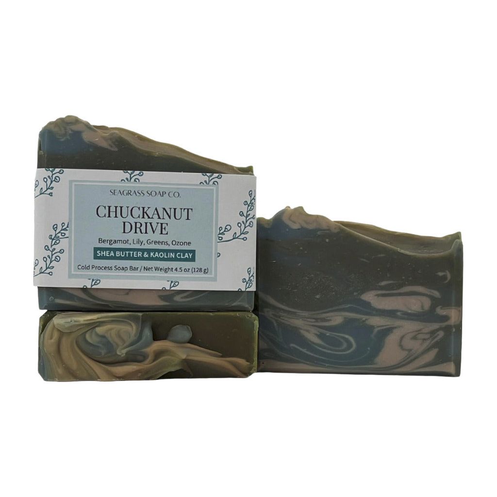 Three soap bars, one displaying the label, one showing the top design, the other showing the side with swirls of green, blue and cream