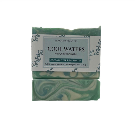 Two retangular soap bars, one displays the label, the other the top design. Colors are light green, blue and white