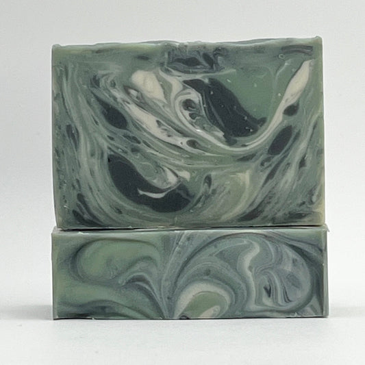 Forest natural, ocean water soap bar enriched with coconut milk and shea butter and scented with woodsy essential oils with black, green and white swirls on a white background by Seagrass Soap Co.