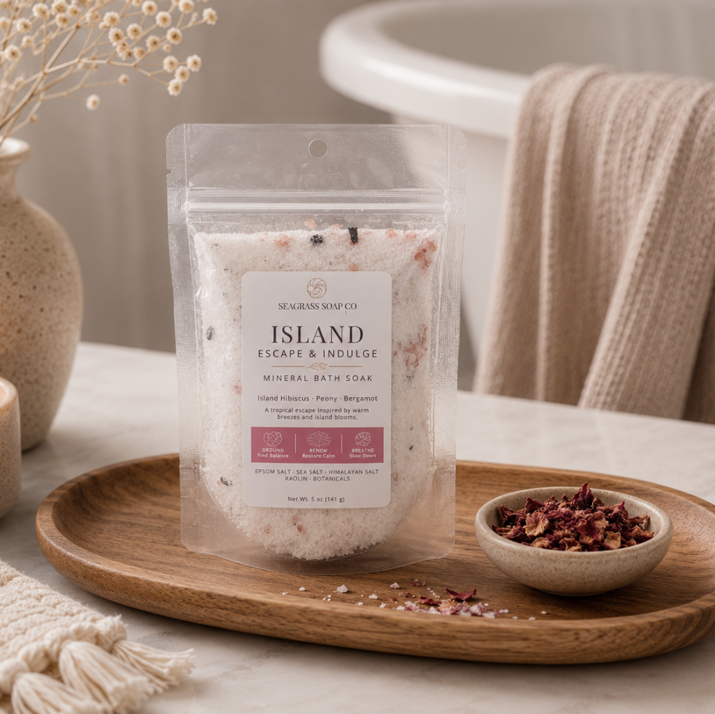 Island mineral bath soak package displayed on a wooden tray next to a bowl of botanicals in a bathroom setting