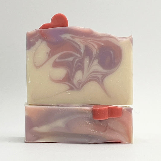 Waves of Love soap with a soap heart on top of a white base bar with pink and purple swirl design on a white background.