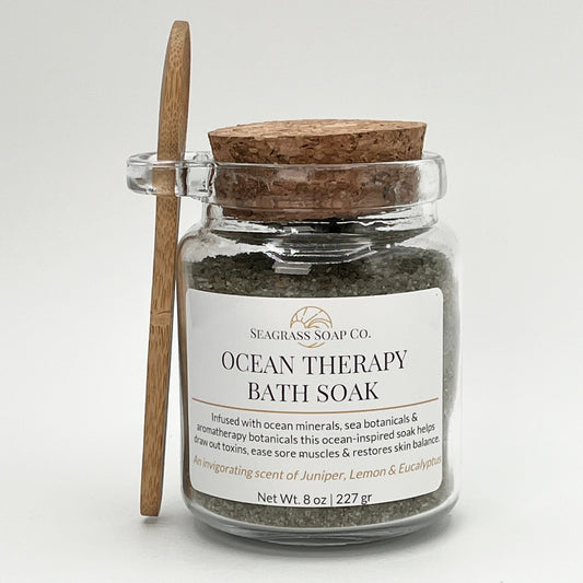 Ocean Therapy Bath Soak in a jar with a wooden spoon on a white background and a cork lid.