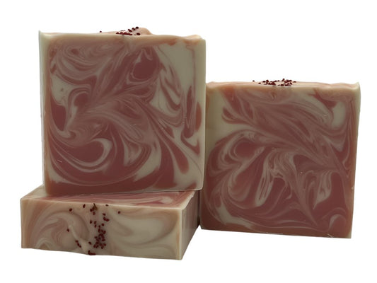 Three bars of peppermint swirl soap bars adorned with cranberry seeds on top.