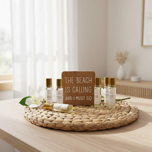 Roll on perfume bottles with labels on a woven surface with a sign reading 'The Beach is Calling and I Must Go'.