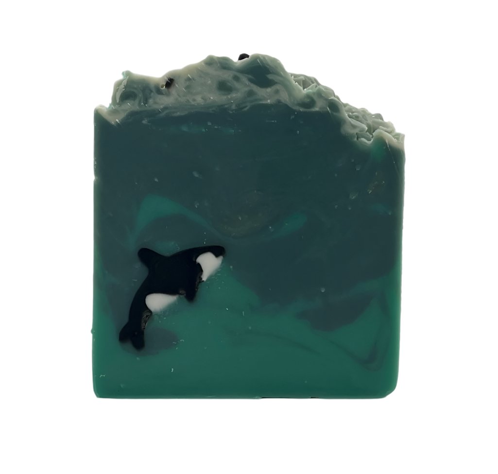 A handmade orca embedded in a soap bar swimming in the Salish Sea of green and blue swirls.