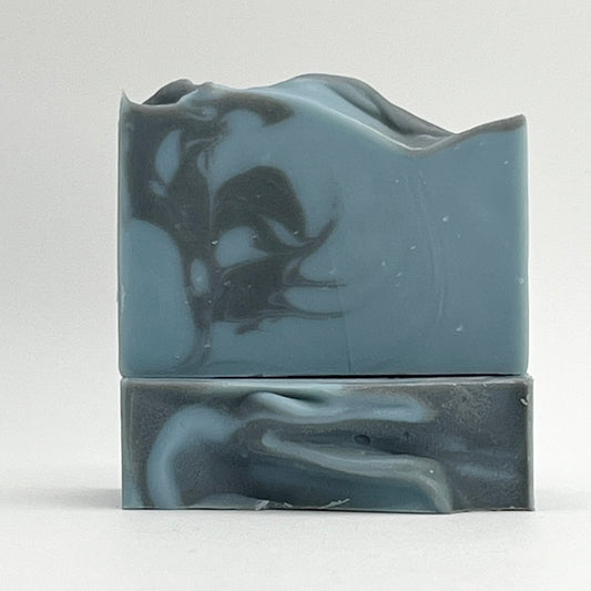 Salty Mariner ocean water soap bar with a blue base and a black swirl on a white background by Seagrass Soap Co.