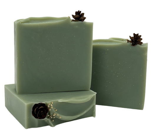 Three soap bars in a solid evergreen color with a real miniature pine cone on top. 