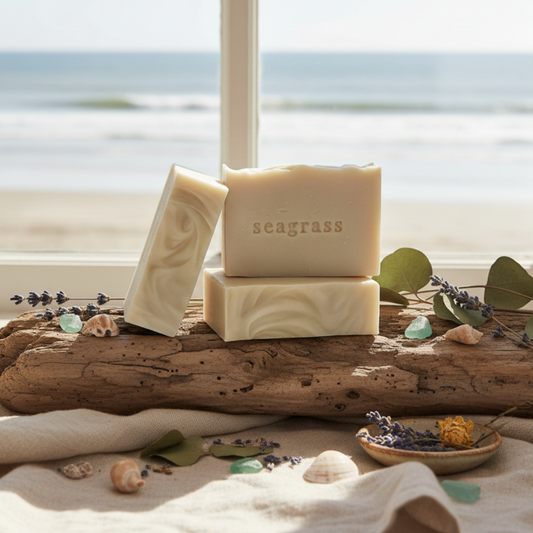 Three seaside cottage handmade soap bars in a warm cream color, featuring one standing upright, one leaning, and one stacked on top. The top bar is embossed with the word 'seagrass'.