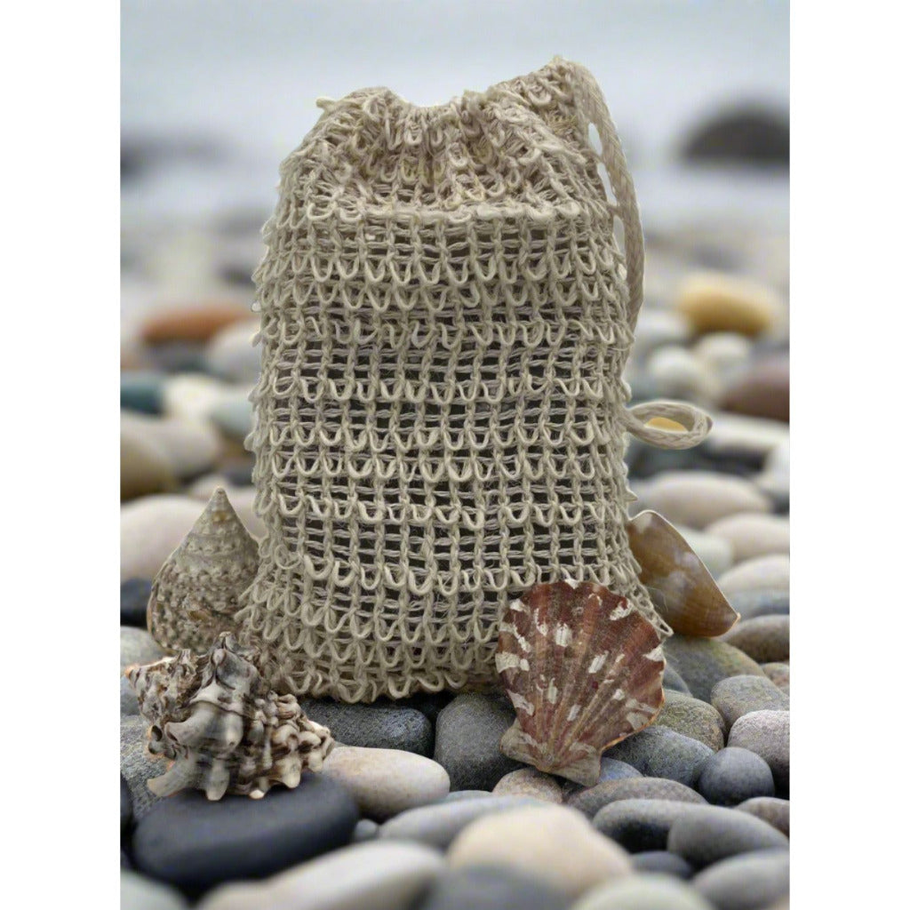 A close up view of a sisal soap saver pouch sitting on a rocky beach