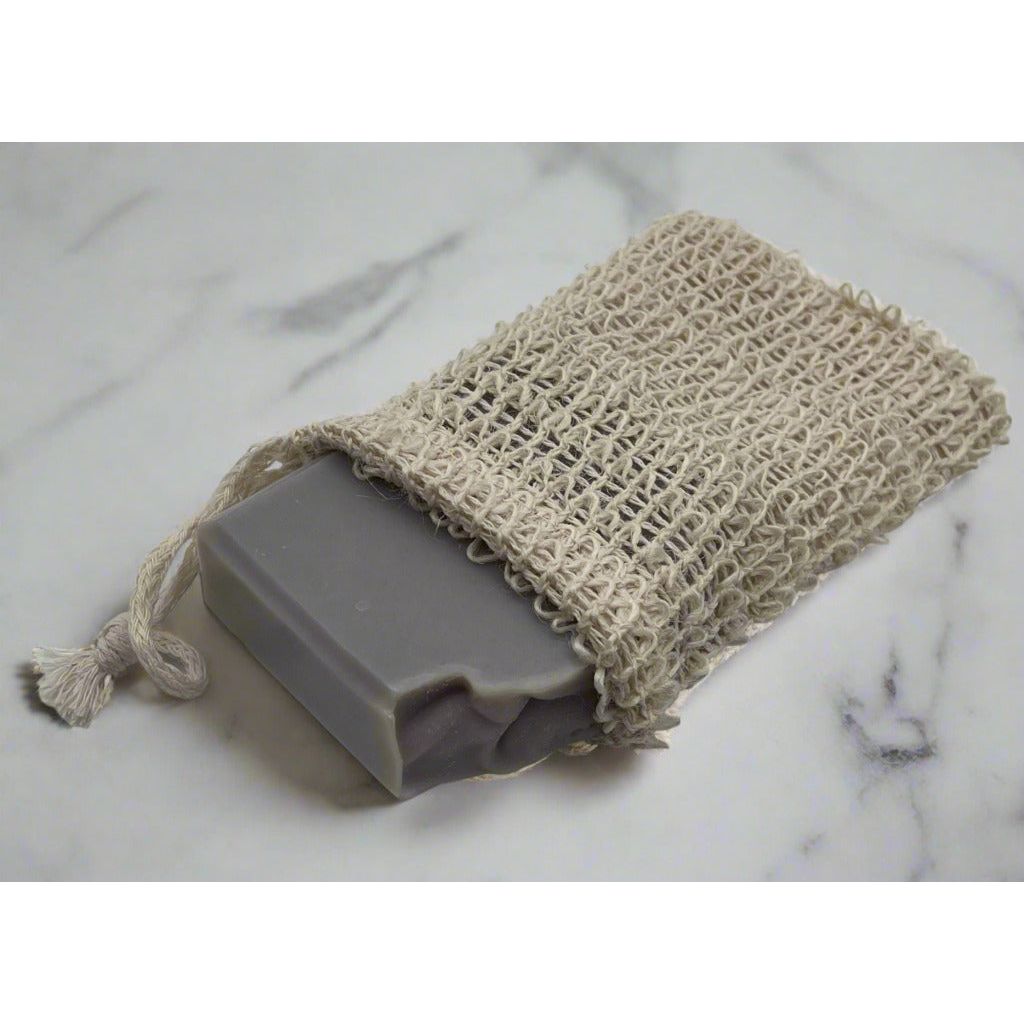 A close up view of a soap saver pouch with a full size soap bar sitting on a marble counter